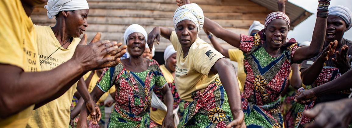 Women dancing together in colorful traditional skirts during a community gathering in the Democratic Republic of Congo.