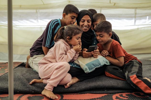 Family in Gaza gathering around a mobile phone 