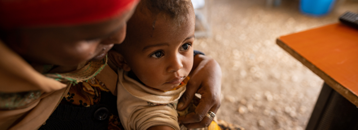 A child held by a caregiver at a health facility in Sudan