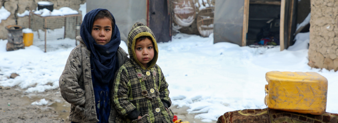 Afghan children standing on muddy field around the makeshift tent during winter season in Kamber district of Kabul, Afghanistan