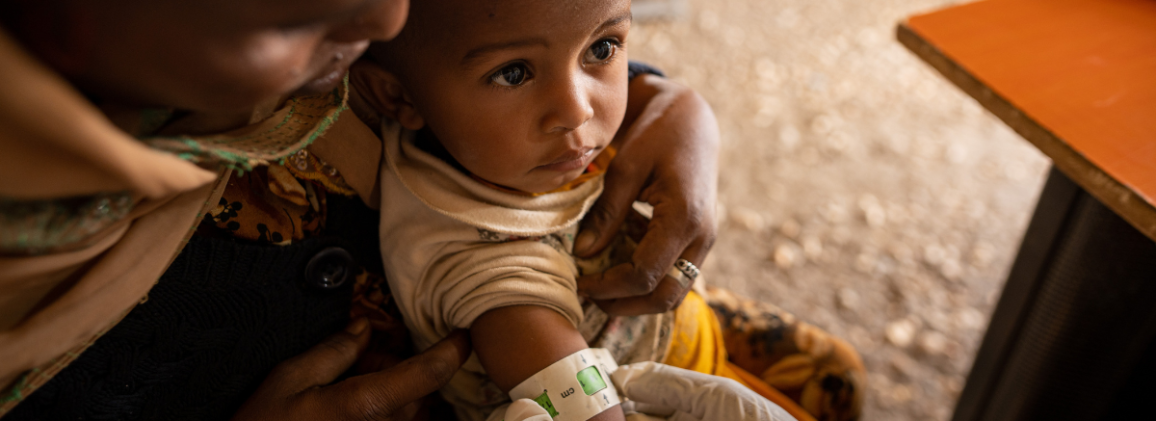A child held by a caregiver at a health facility in Sudan