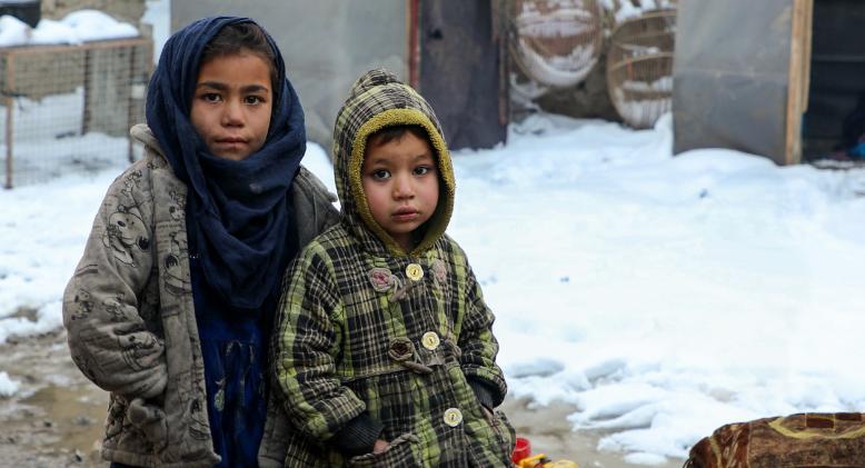Afghan children standing on muddy field around the makeshift tent during winter season in Kamber district of Kabul, Afghanistan