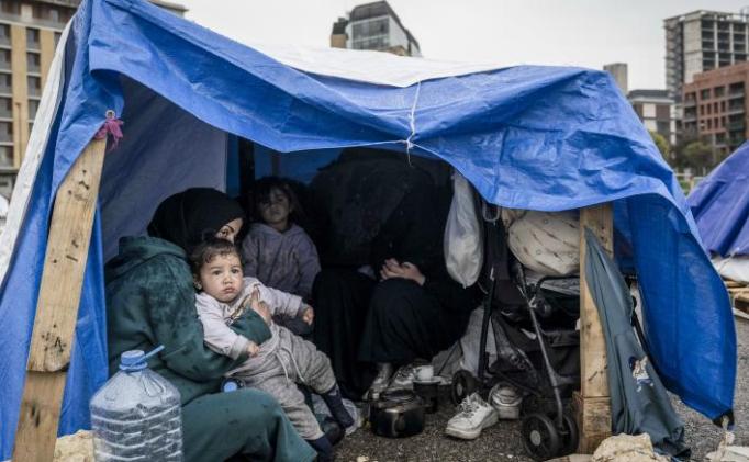 Women and children are sheltering under a tent.
